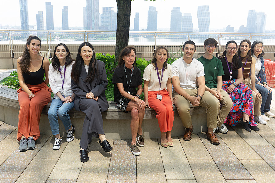 Members of the Skok Lab sitting together on a rooftop terrace with the Manhattan skyline behind them.